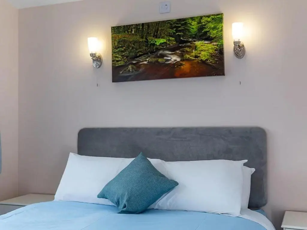 a bedroom with a bed with a painting on the wall at Kilninver Chalet on Reelig Estate in Kirkhill