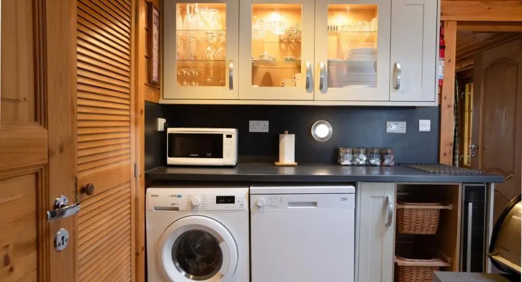 a kitchen with a washing machine and a microwave at Beaver Creek Lodge in Aviemore
