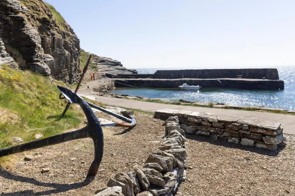 a pair of scissors on a stone wall next to the water at Craiglea Lodge in Latheron