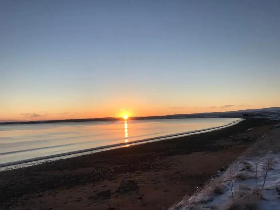 a sunset on the beach with the sun setting at 3-Bedroom Eco-house with EV charger. in Rosemarkie