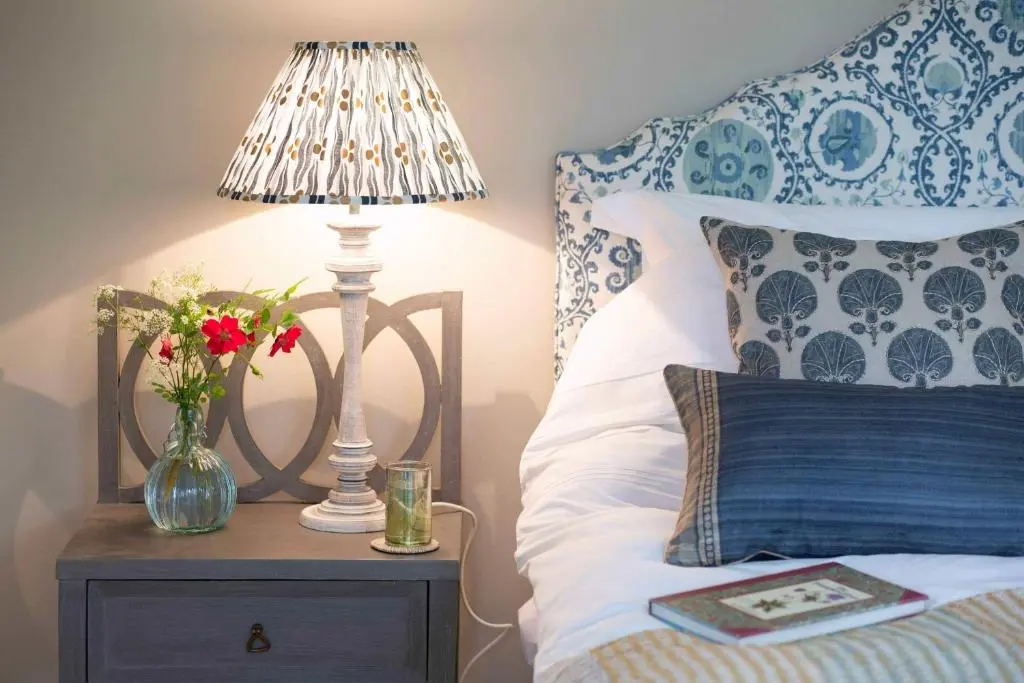 a bed with a lamp and a vase of flowers on a table at Milton Lodge - Seasgair Lodges in Newtonmore