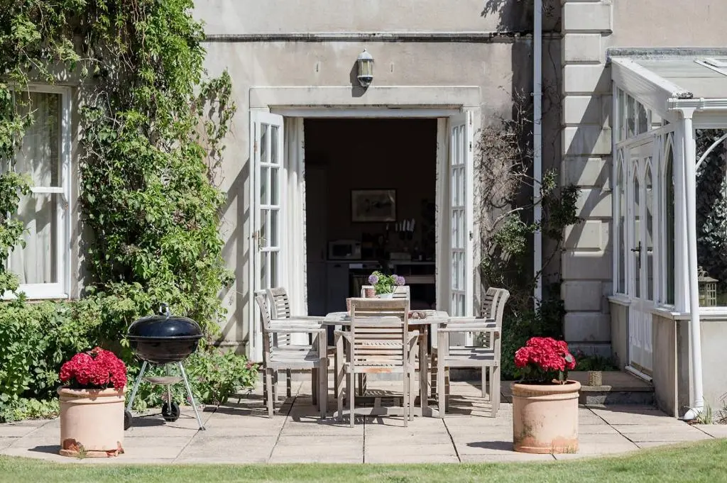 a patio with a table and chairs and a grill at Milton Lodge - Seasgair Lodges in Newtonmore