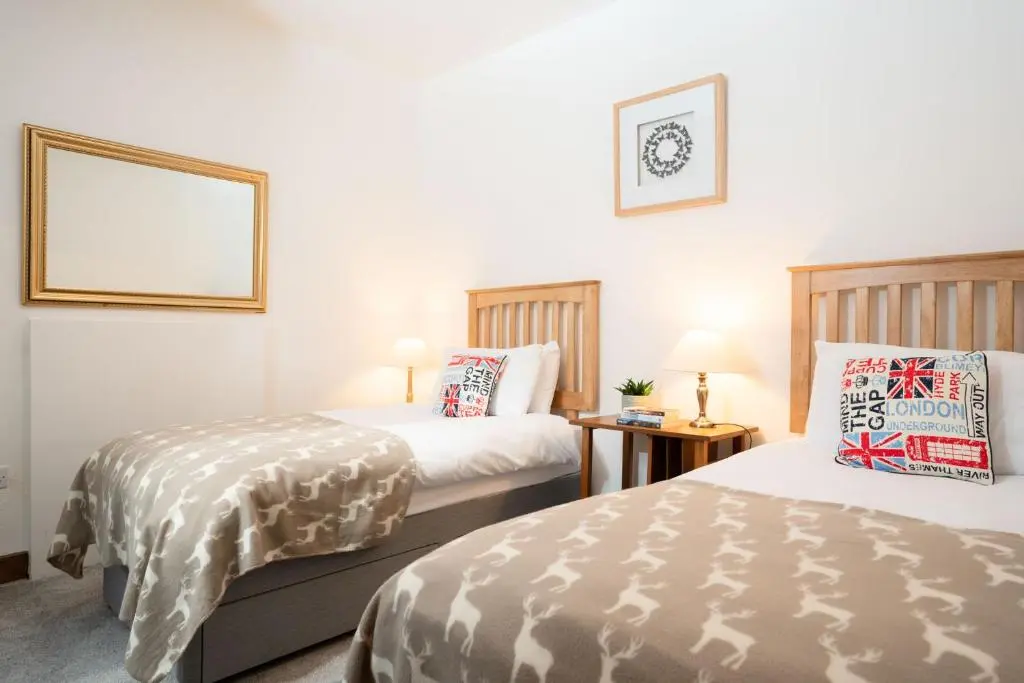a hotel room with two beds and a picture on the wall at Douglas Cottage - Seasgair Lodges in Boat of Garten