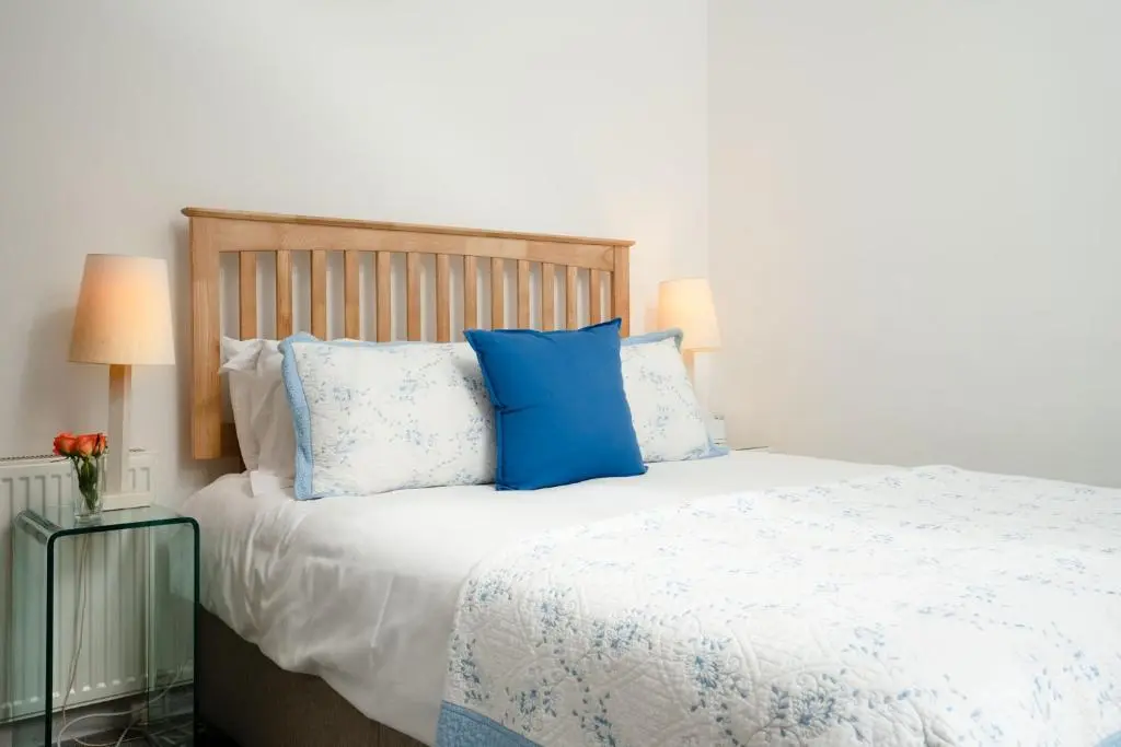 a bedroom with a bed with blue and white pillows at Douglas Cottage - Seasgair Lodges in Boat of Garten