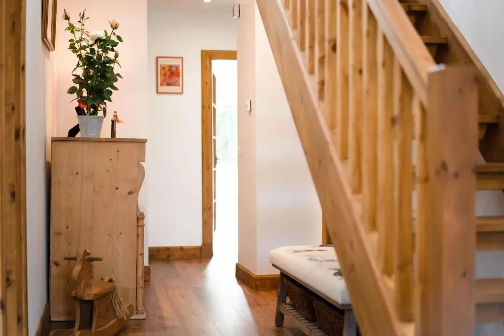 a hallway with a wooden staircase and a plant at Douglas Cottage - Seasgair Lodges in Boat of Garten