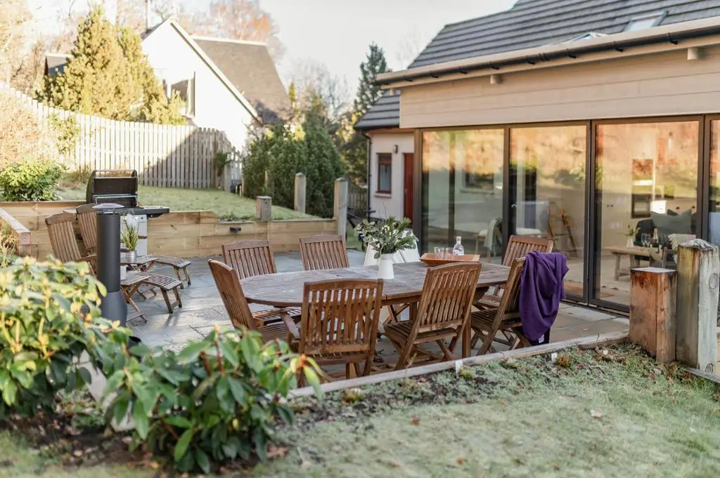 a patio with a wooden table and chairs at Oak Cottage - Seasgair Lodges in Kincraig