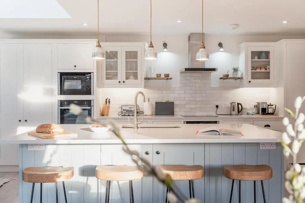 a kitchen with white cabinets and bar stools at Oak Cottage - Seasgair Lodges in Kincraig