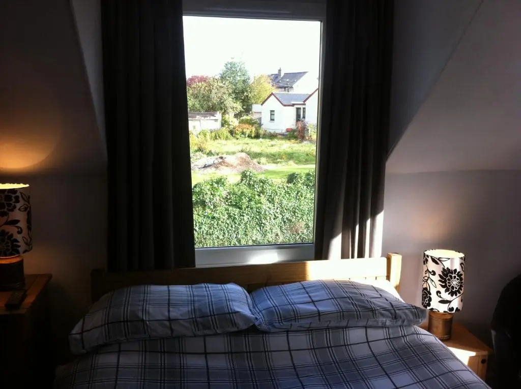a bedroom with a bed and a large window at The Whitehouse in Dingwall
