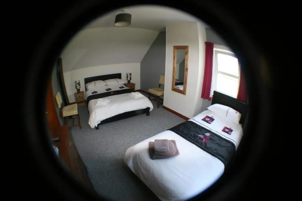 a view of a bedroom with two beds and a mirror at The Whitehouse in Dingwall