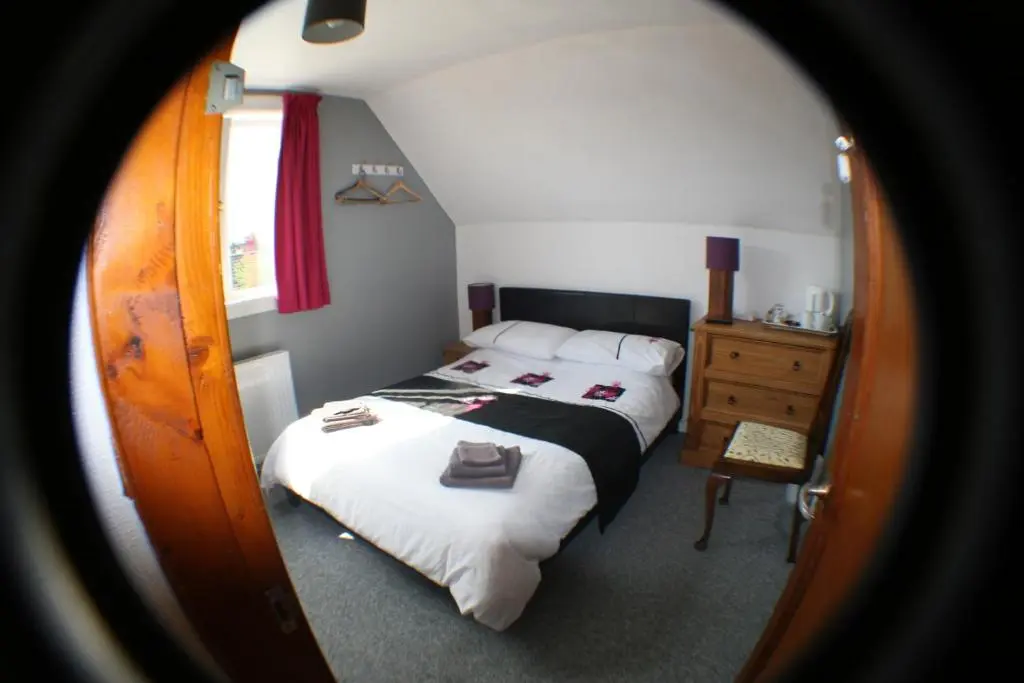 a small bedroom with a bed and a dresser at The Whitehouse in Dingwall