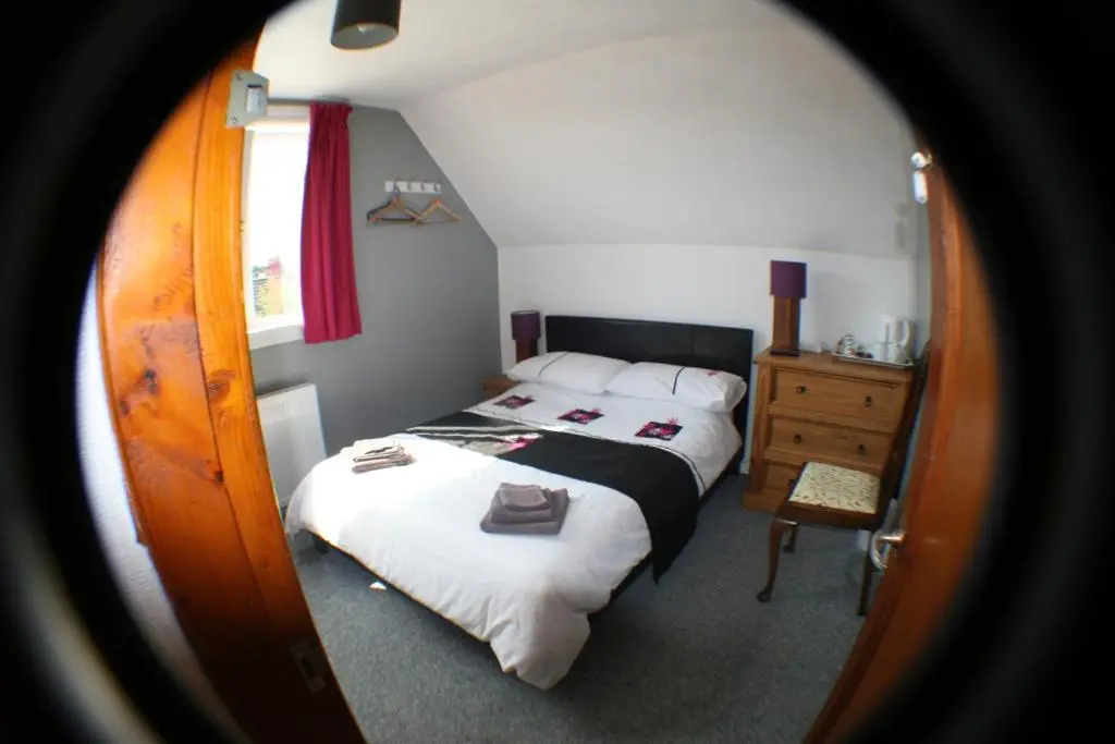 a small bedroom with a bed and a dresser at The Whitehouse in Dingwall
