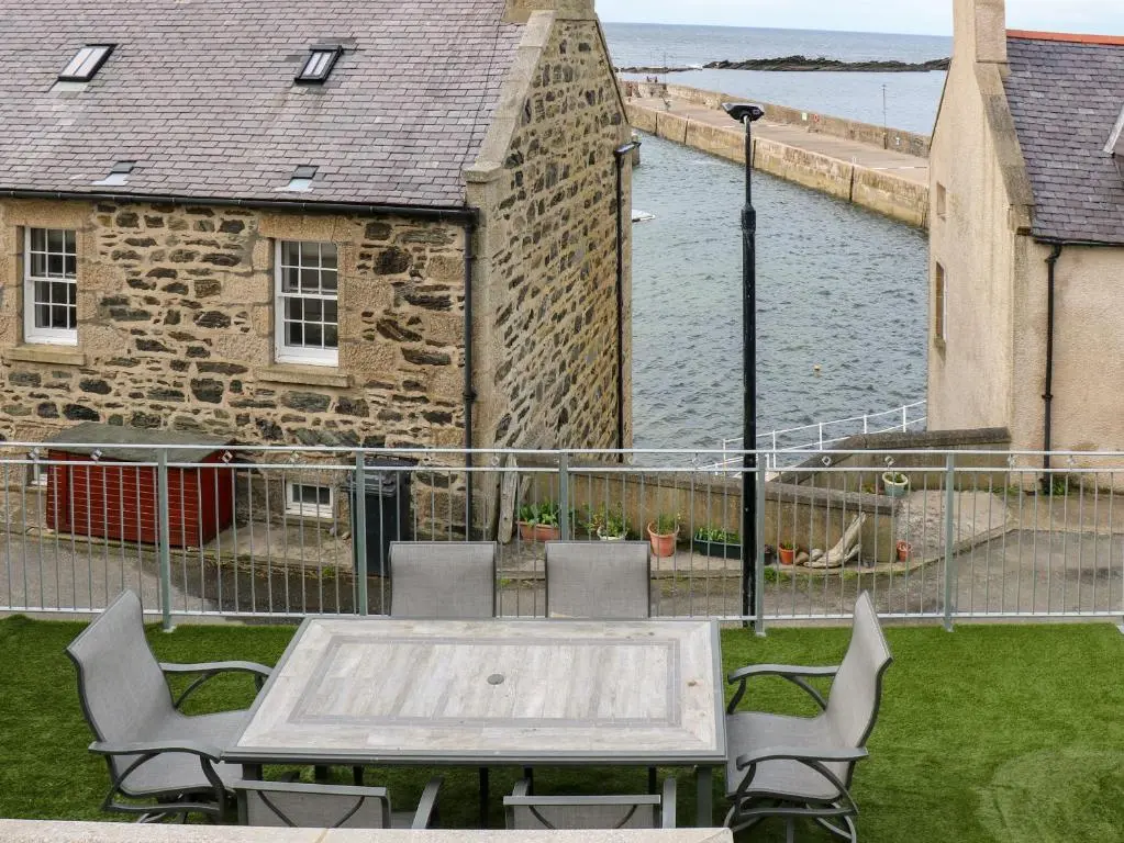 a table and chairs on a patio with a view of the water at Craignure in Banff