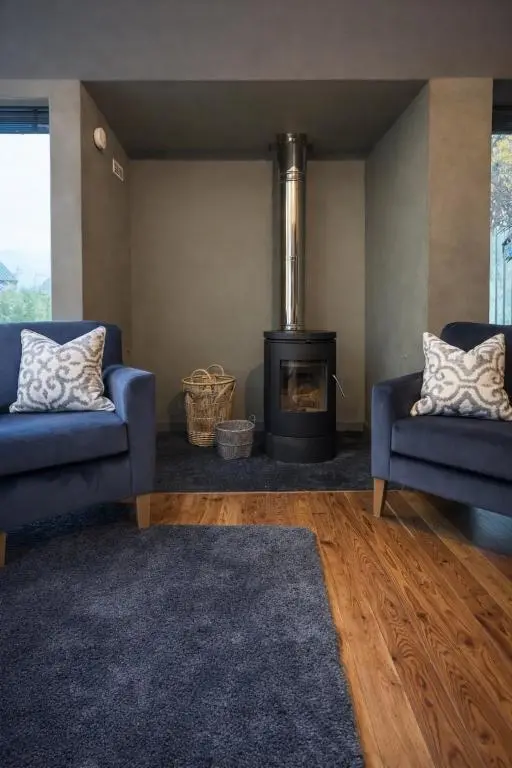a living room with two blue chairs and a fireplace at The Highland MoonRay in Inverness