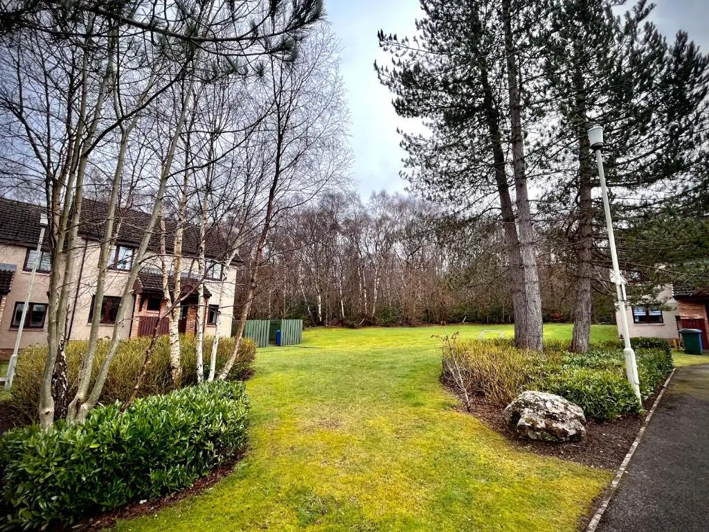 a yard with a house and some trees and grass at Comfortable, modern apartment with parking. Inverness. in Inverness