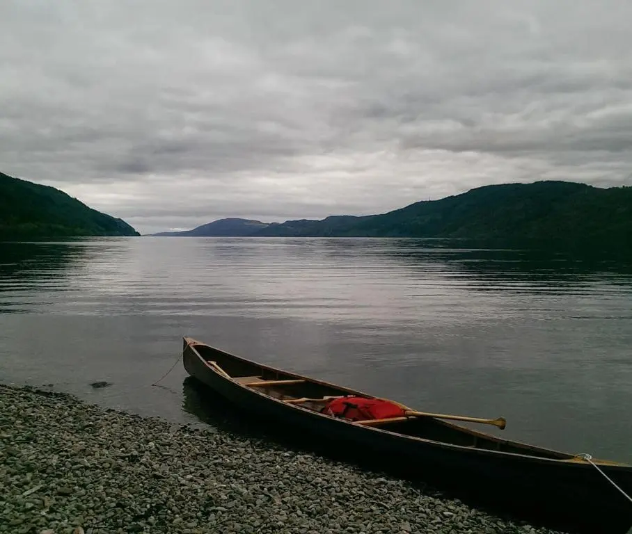 a canoe sitting on the shore of a lake at Comfortable, modern apartment with parking. Inverness. in Inverness