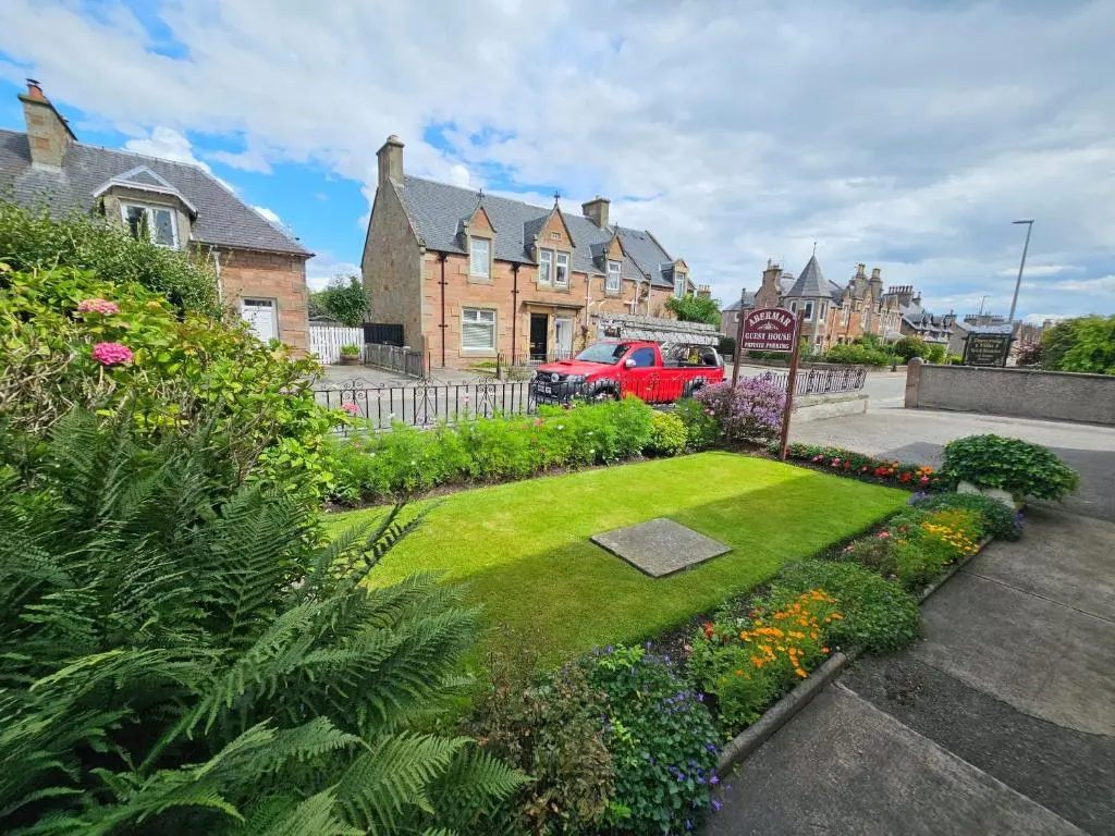 a garden in a residential neighborhood with houses and flowers at mySTAYINN Abermar 12 Bedroom House in Inverness