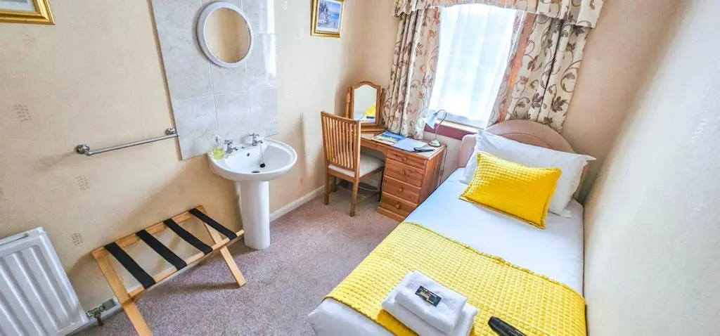 a small bathroom with a sink and a bed and a mirror at mySTAYINN Abermar 12 Bedroom House in Inverness
