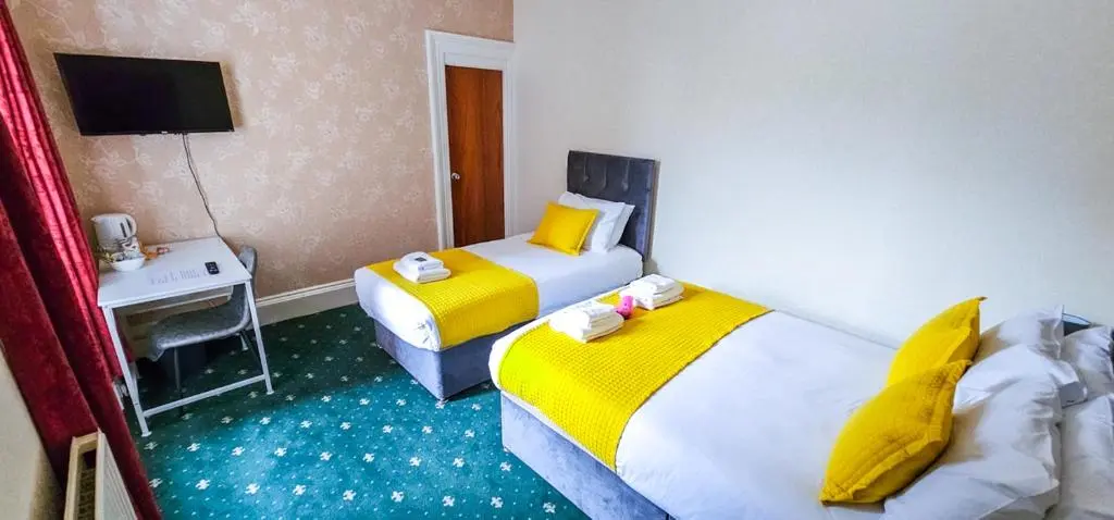 a hotel room with two beds and a television at mySTAYINN Abermar 12 Bedroom House in Inverness