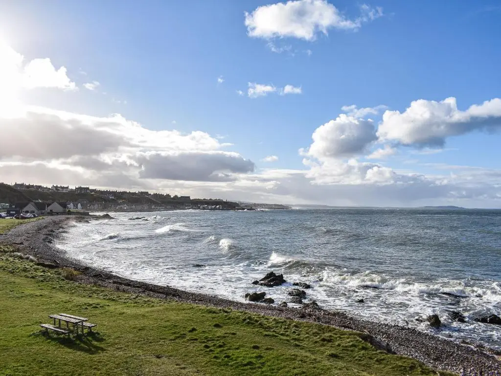 a bench sitting on the shore of a beach at Strathlene Lodge in Ianstown