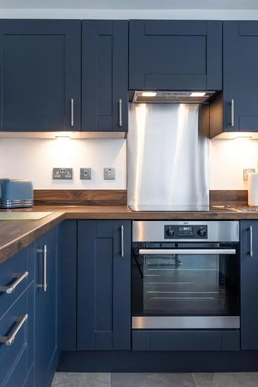 a kitchen with navy blue cabinets and an oven at Fletcher's Gate in Inverness