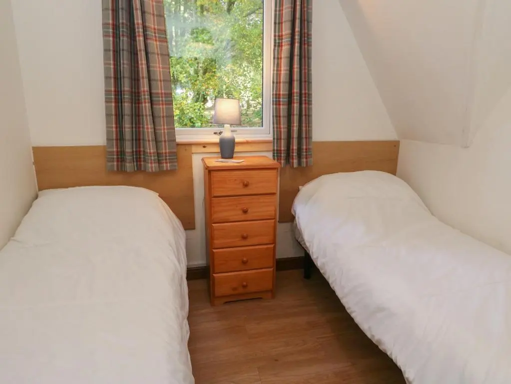 two twin beds in a room with a window at 27 Invergarry Lodges in Spean Bridge