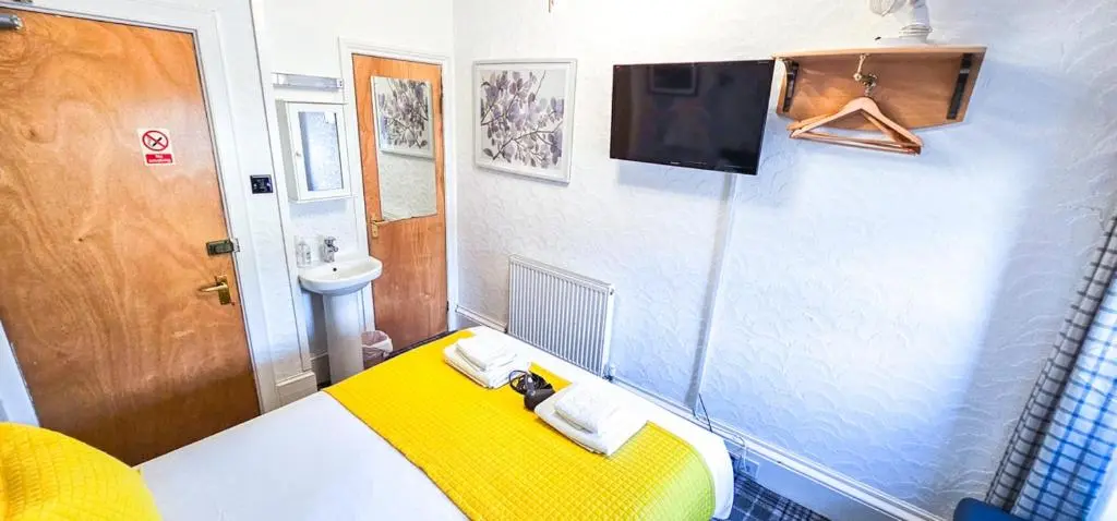 a small room with a yellow bed and a sink at mySTAYINN Kinloch 7 Bedroom House in Inverness