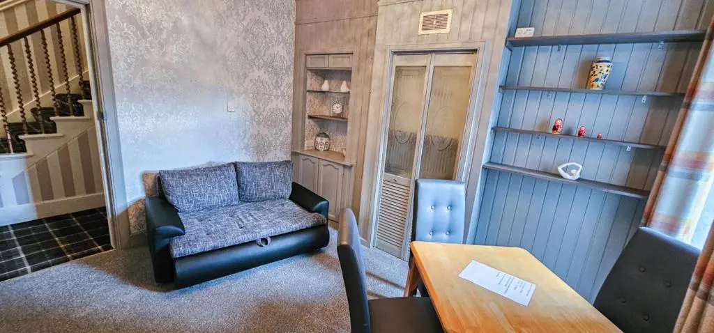 a living room with a chair and a table at mySTAYINN Kinloch 7 Bedroom House in Inverness
