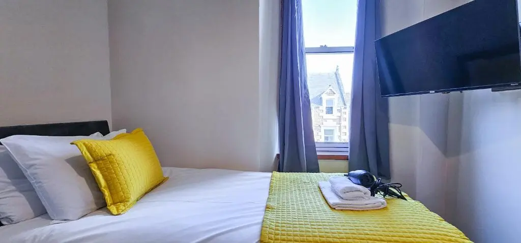 a bedroom with a bed with yellow pillows and a window at mySTAYINN Melrose Villa in Inverness