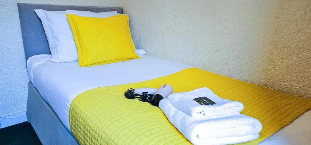 a bed with towels and a camera on top of it at mySTAYINN Telford Guest House in Inverness