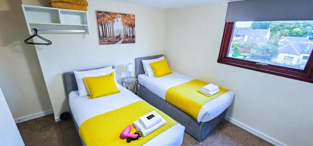 two beds in a small room with a window at mySTAYINN Telford Guest House in Inverness