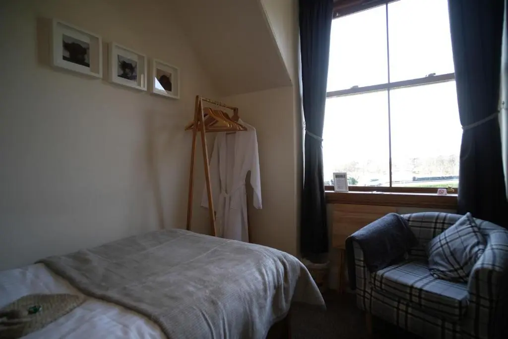 a bedroom with a bed and a chair and a window at Morlea Bed & Breakfast in Drumnadrochit
