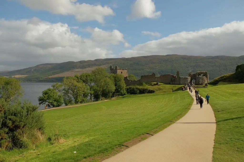a group of people walking on a path in front of a castle at Morlea Bed & Breakfast in Drumnadrochit