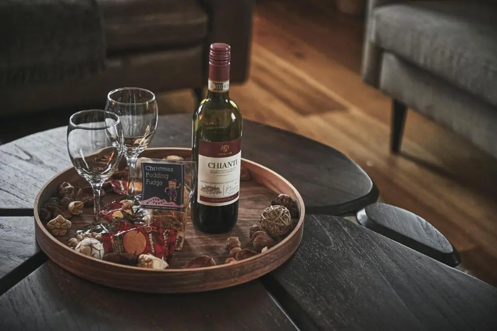 a bottle of wine and two glasses on a table at The Steadings, Aviemore Luxury 5 star rated 3 Bed with home cinema garden and parking in Aviemore