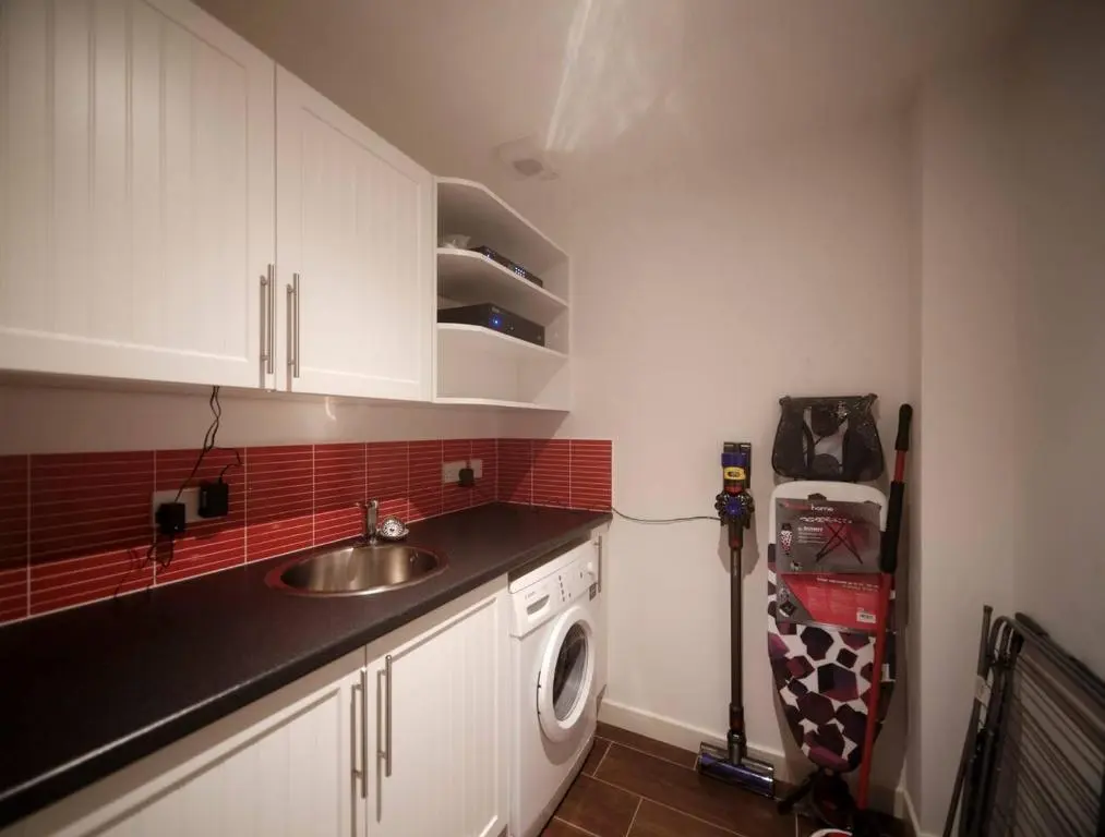 a kitchen with a sink and a washing machine at The Steadings, Aviemore Luxury 5 star rated 3 Bed with home cinema garden and parking in Aviemore