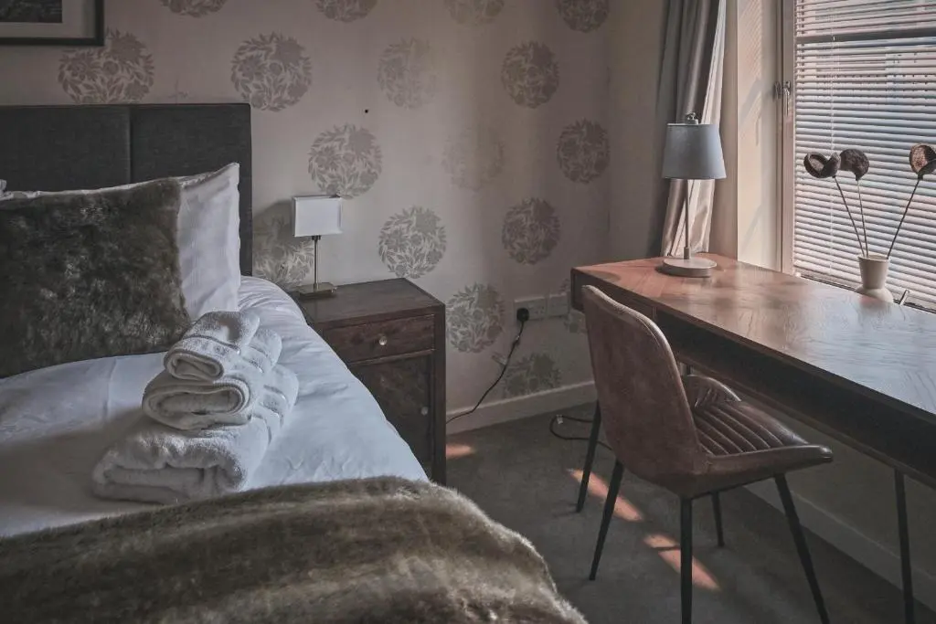 a bedroom with a desk and a bed with a chair at The Steadings, Aviemore Luxury 5 star rated 3 Bed with home cinema garden and parking in Aviemore
