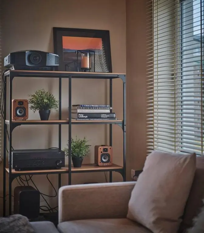 a living room with a couch and a shelf with speakers at The Steadings, Aviemore Luxury 5 star rated 3 Bed with home cinema garden and parking in Aviemore