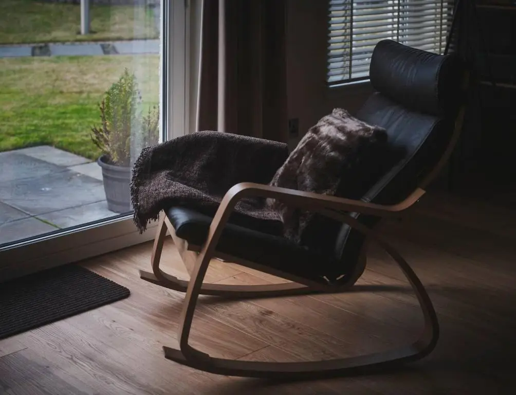 a rocking chair sitting in front of a window at The Steadings, Aviemore Luxury 5 star rated 3 Bed with home cinema garden and parking in Aviemore