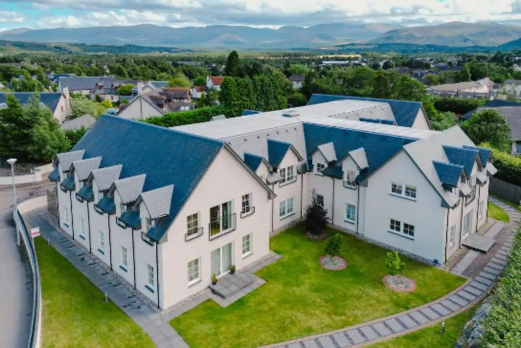 an aerial view of a large white house with blue roofs at The Steadings, Aviemore Luxury 5 star rated 3 Bed with home cinema garden and parking in Aviemore