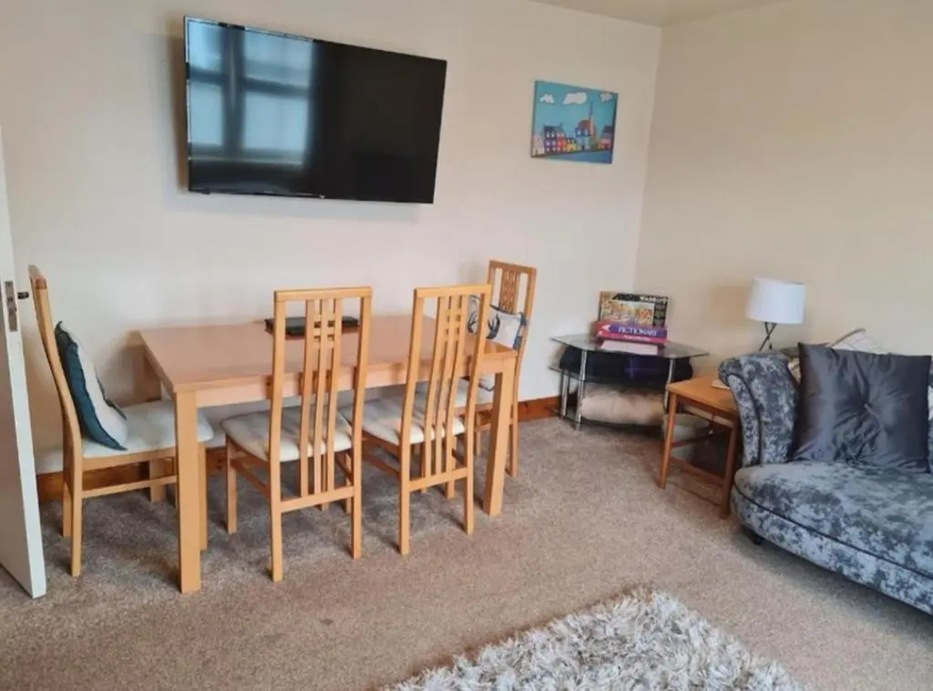 a living room with a table and chairs and a tv at Ness City Apartment in Inverness
