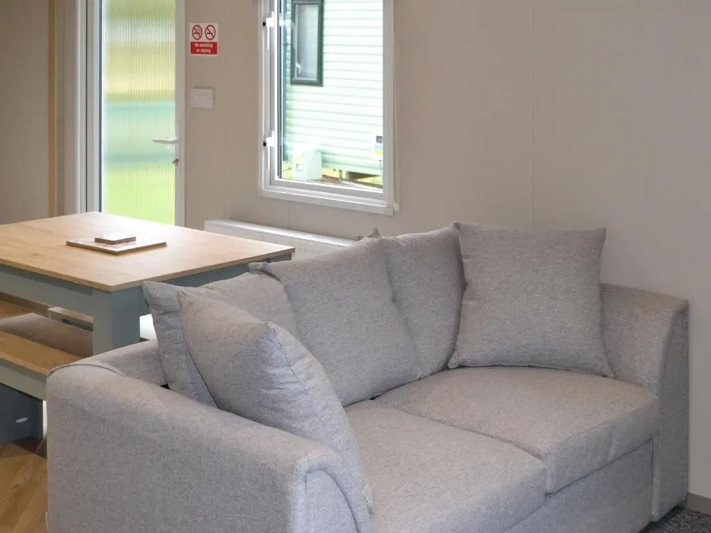 a couch in a living room with a table and a window at The Finch in Dyke