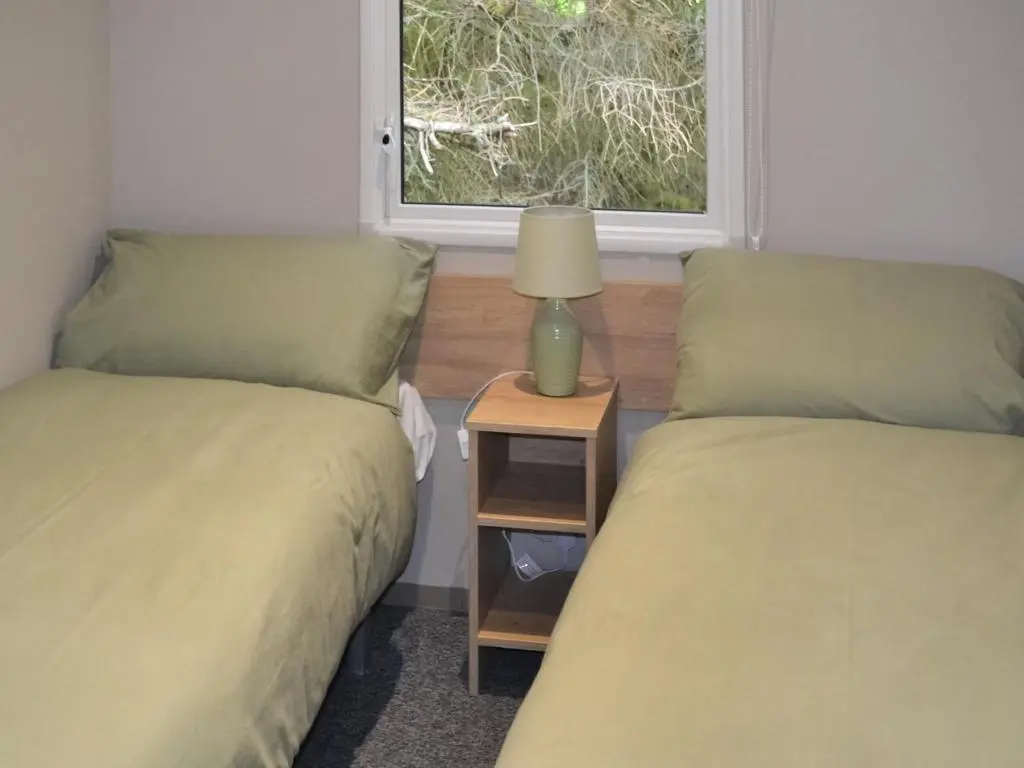 two beds in a room with a window at The Finch in Dyke