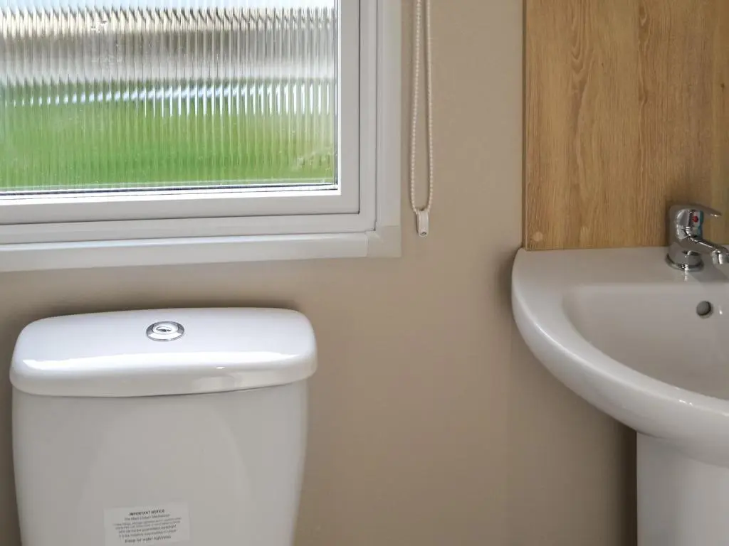 a bathroom with a toilet and a sink and a window at The Falcon - Uk45538 in Dyke