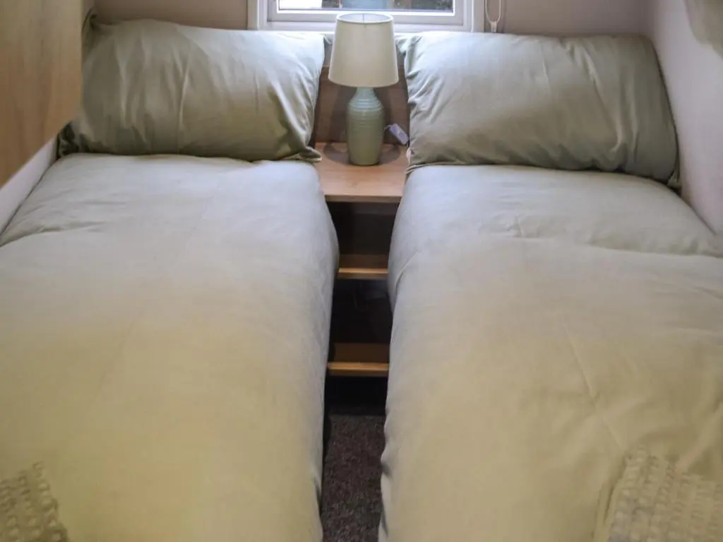 two beds sitting next to a table with a lamp at The Falcon - Uk45538 in Dyke