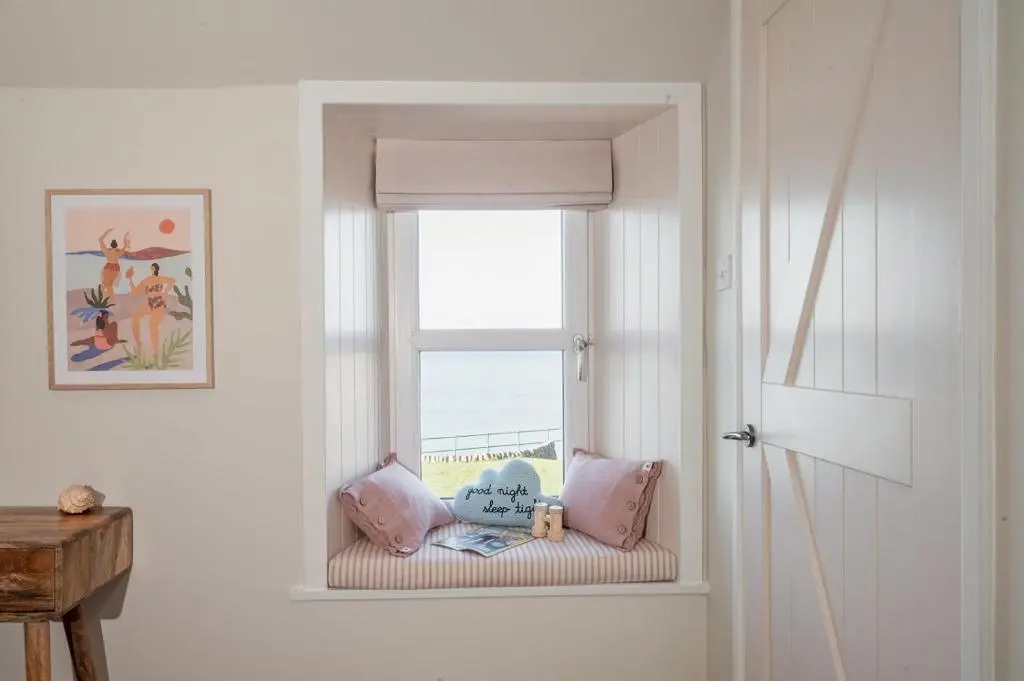 a window seat in a room with a view of the ocean at Ina's Cottage - Seasgair Lodges in Portmahomack
