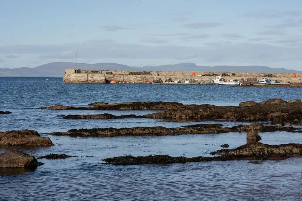 a large body of water with rocks in the water at Ina's Cottage - Seasgair Lodges in Portmahomack