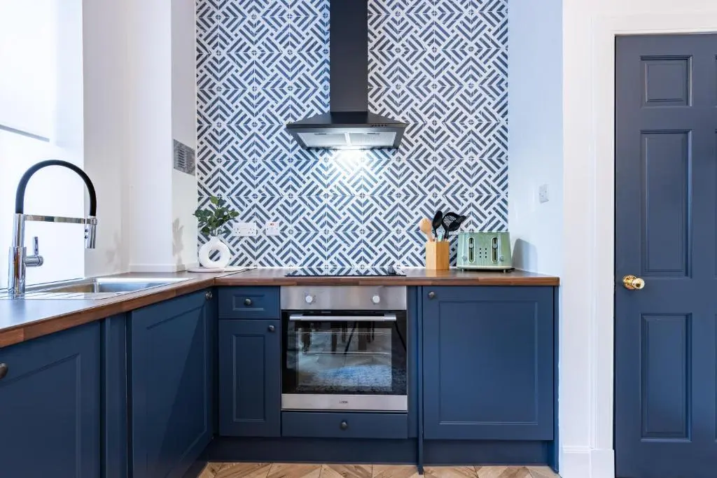 a kitchen with blue cabinets and a blue wall at The Wee Gem in Inverness