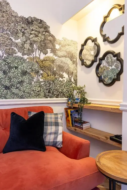 an orange couch in a living room with a wall mural at The Wee Gem in Inverness