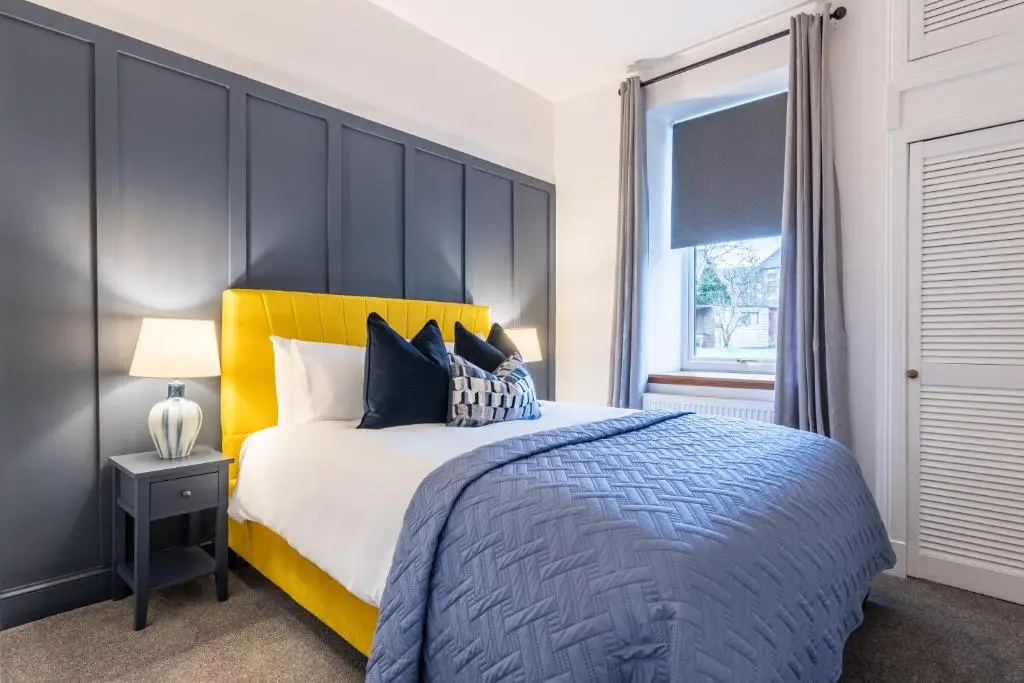 a bedroom with a large bed with a yellow headboard at The Wee Gem in Inverness