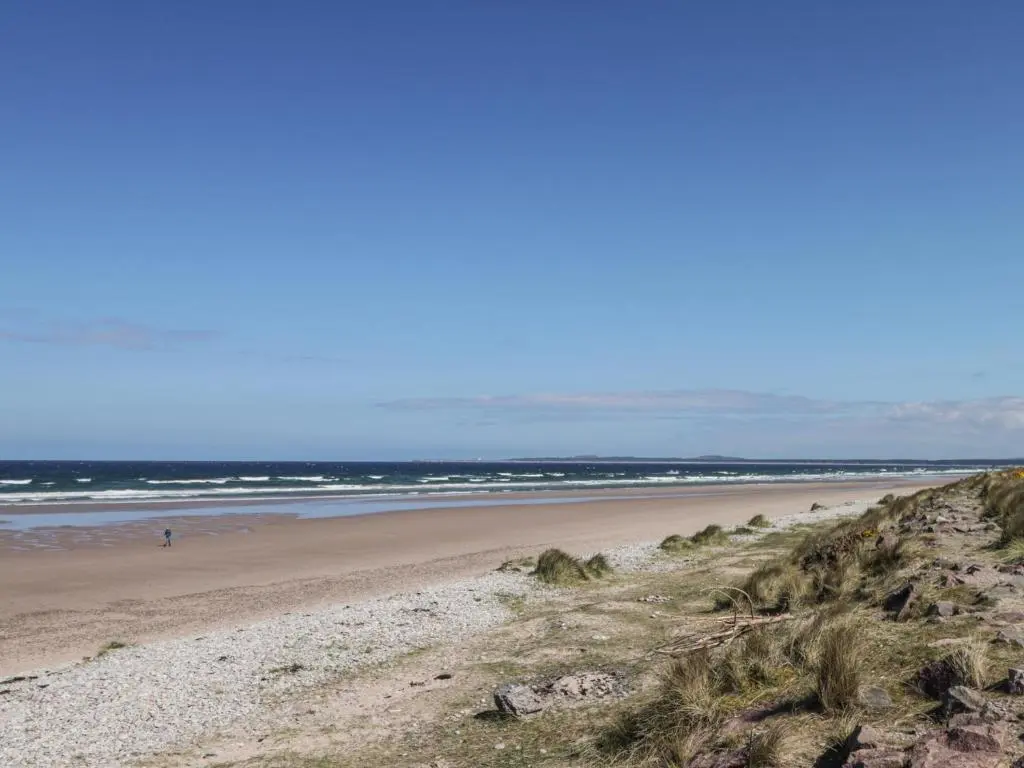 a beach with people walking on the sand and the ocean at Easter Blervie in Forres