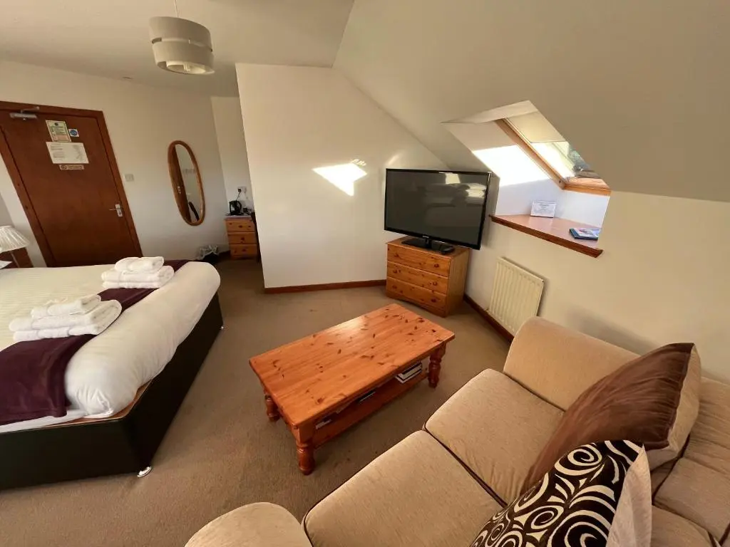a living room with a couch and a tv at Smithton Hotel in Inverness